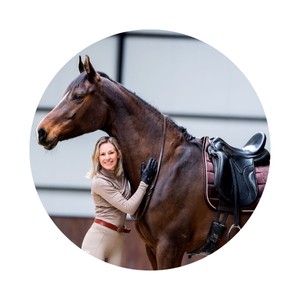 Yvet Blokesch leans against a brown horse and smiles.