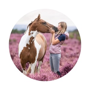 Yvet Blokesch stands in a heath with a piebald and kisses it on the muzzle.